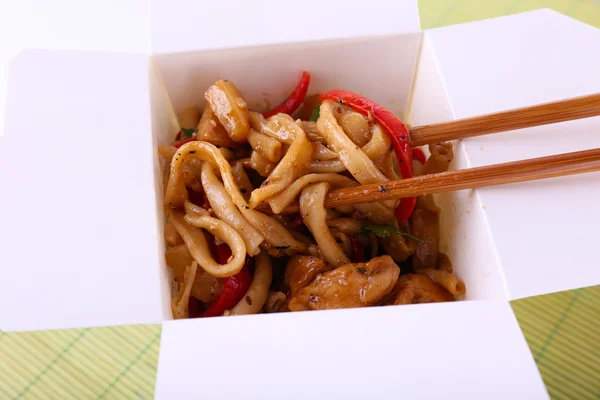 Fried noodles in takeaway box on mat background — Stock Photo, Image