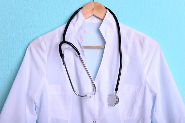 Arts jas met stethoscoop op hanger op blauwe achtergrond — Stockfoto