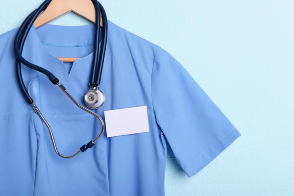 Camisa médica con estetoscopio en percha sobre fondo azul —  Fotos de Stock