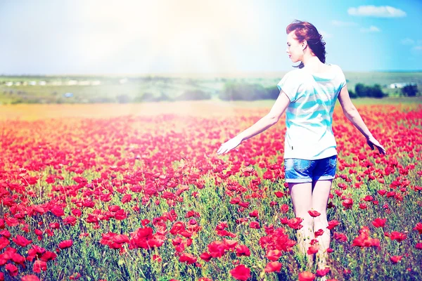 Mooie jonge vrouw in poppy bloemen veld — Stockfoto