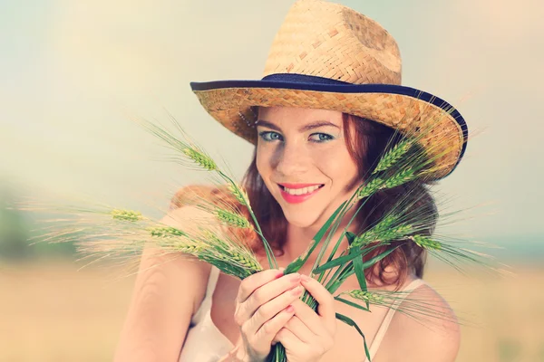 Beautiful young woman with ears in field — Stock Photo, Image