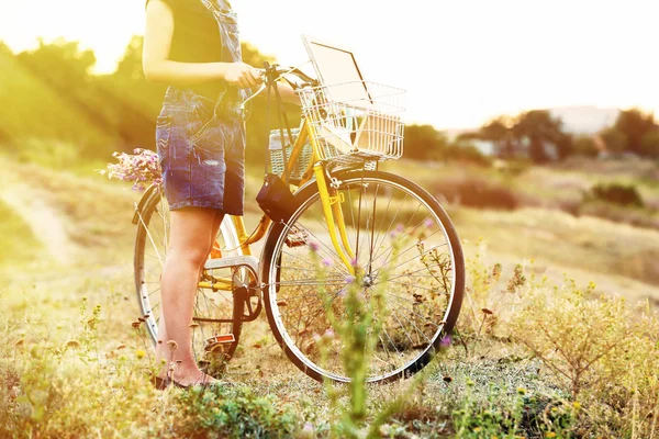 Ung kvinna med cykel på ängen — Stockfoto