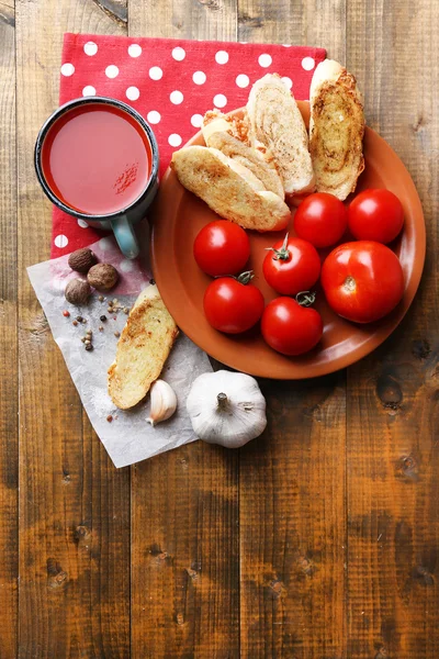 Domácí rajčatové šťávy v barevný hrnek, toasty a čerstvá rajčata na dřevěné pozadí — Stock fotografie