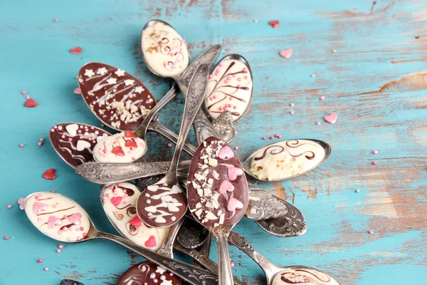 Spoons with tasty chocolate for party on old blue wooden table — Stock Photo, Image