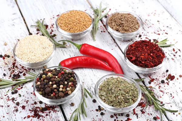 Spices in glass round bowls with herbs and chilly pepper on wooden background — Stock Photo, Image