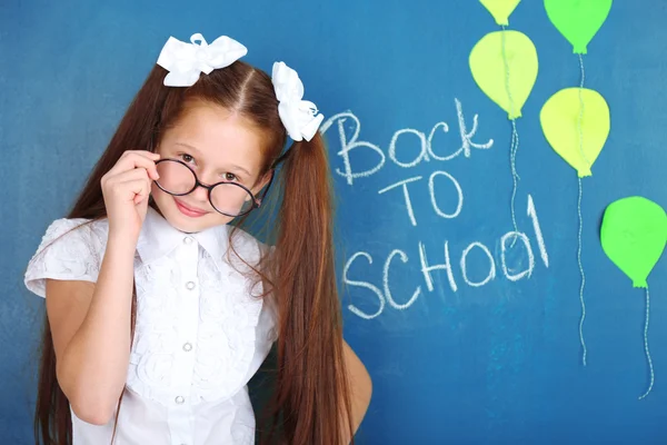 Cute girl standing near blackboard in classroom — Stock Photo, Image