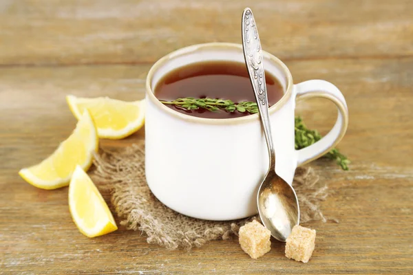 Xícara de chá de ervas saboroso com tomilho e limão na mesa de madeira — Fotografia de Stock