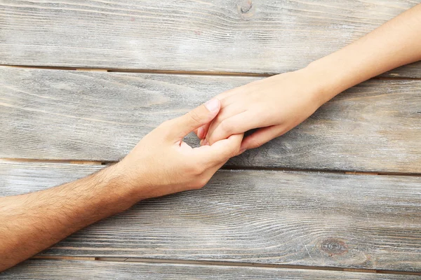 Pareja cariñosa cogida de las manos de cerca sobre fondo de madera —  Fotos de Stock