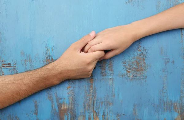 Amante casal de mãos dadas close-up no fundo de madeira — Fotografia de Stock