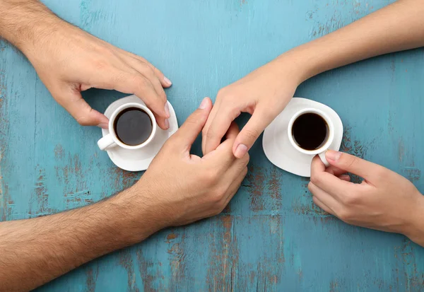 Loving couple with hot drinks on table — Stock Photo, Image