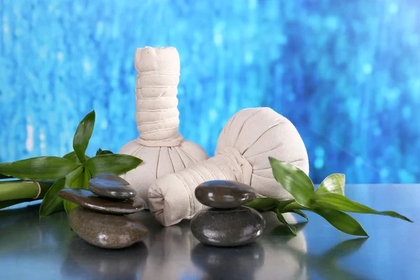 Composición del spa con bolsas de masaje a base de hierbas y bambú sobre la mesa sobre fondo azul — Foto de Stock