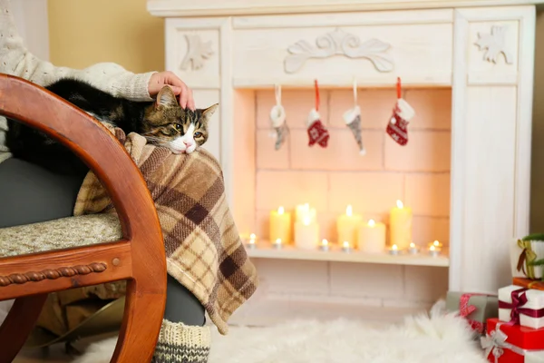 女人和可爱的猫坐在壁炉前的摇椅上 — 图库照片