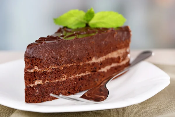 Piece of chocolate cake on plate on light background — Stock Photo, Image