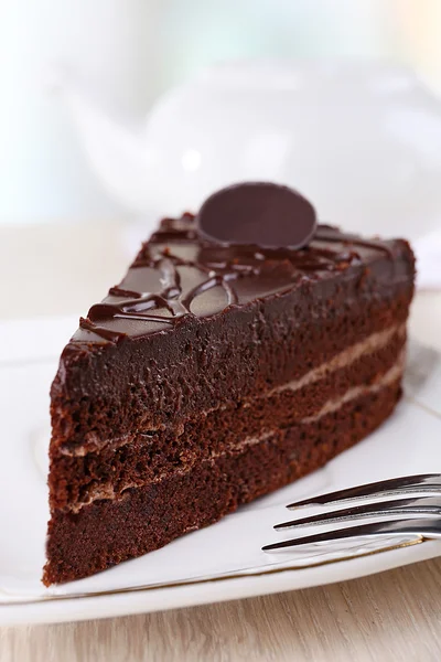 Pedaço de bolo de chocolate na placa no fundo claro — Fotografia de Stock