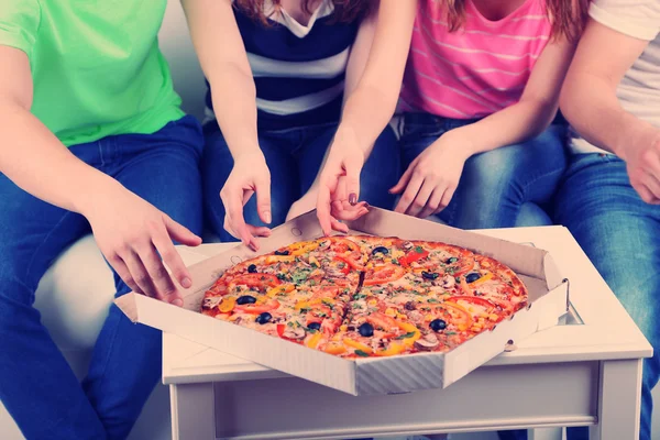 Grupo de jóvenes amigos comiendo pizza en el salón en el sofá —  Fotos de Stock