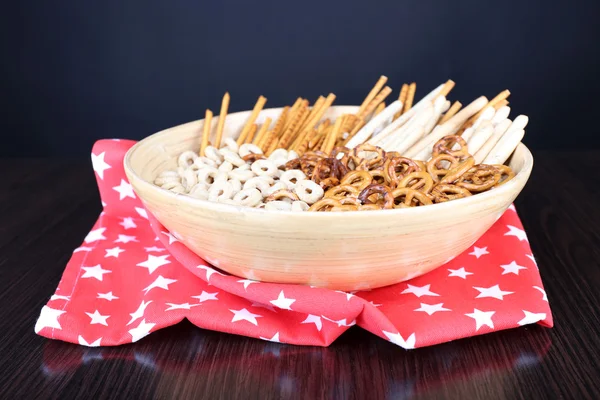 Dry breakfast, sticks and biscuits in a big wooden round bowl on a red napkin on wooden table — Stock Photo, Image