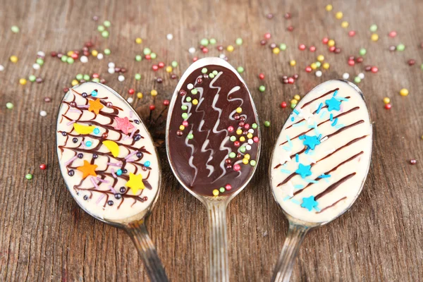 Spoons with tasty chocolate for party on old wooden table — Stock Photo, Image