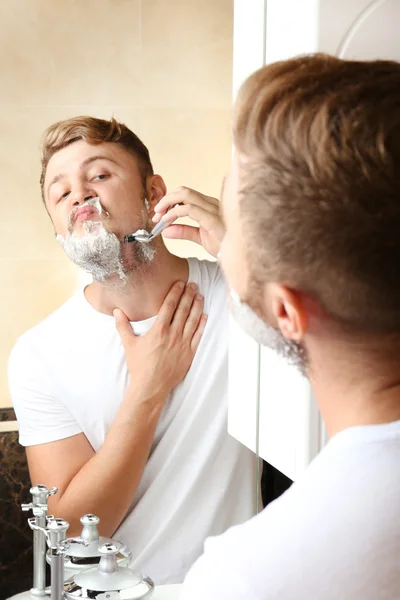 Jeune homme rasant sa barbe dans la salle de bain — Photo