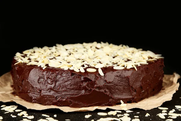 Tasty chocolate cake with almond, on wooden table, on dark background — Stock Photo, Image