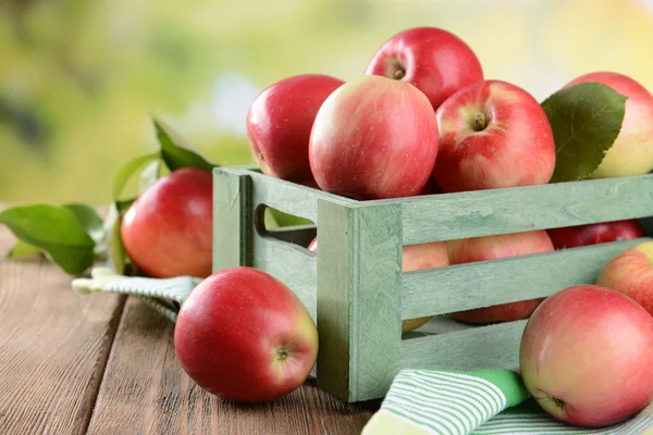 Manzanas dulces en caja de madera sobre mesa sobre fondo brillante —  Fotos de Stock