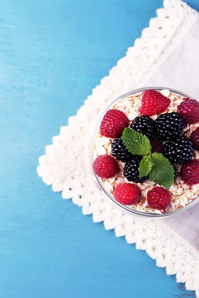 Petit déjeuner sain - yaourt aux fruits frais, baies et muesli servi dans un bocal en verre, sur fond de bois couleur — Photo