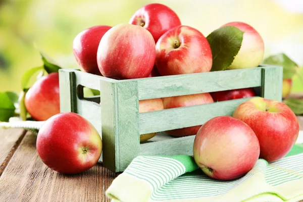 甜的苹果在桌子上明亮的背景上的木盒子里 — 图库照片
