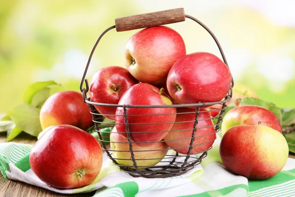 Manzanas dulces en canasta de mimbre sobre mesa sobre fondo brillante — Foto de Stock