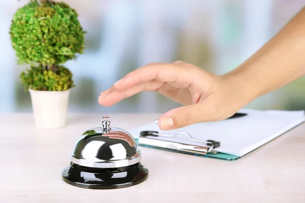 Female hand ring bell on  hotel reception desk, on bright background — Stock Photo, Image