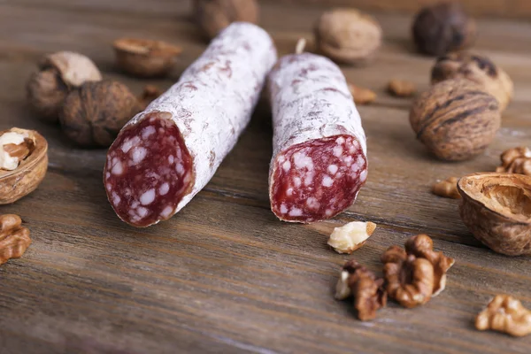 Salame francês e nozes em fundo de madeira — Fotografia de Stock