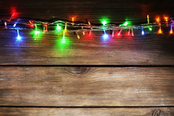 Christmas lights on wooden background — Stock Photo, Image