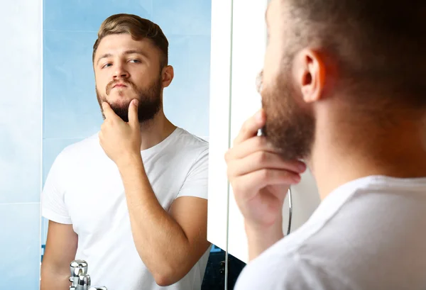 Mladý muž holení jeho vousy v koupelně — Stock fotografie