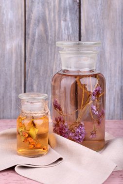 ahşap duvar önünde ahşap bir masa üzerinde bitki tentür şişe