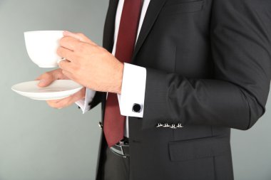 Kahve içme gri arka plan üzerinde siyah elbiseli adam