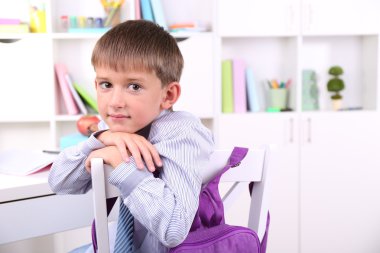 школяр, сидячи на столі в класі