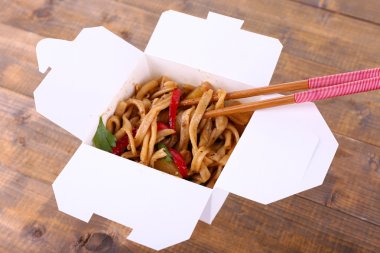 Kızarmış erişte ve paket servisi olan restoran kutusunda ahşap arka plan üzerinde sopa