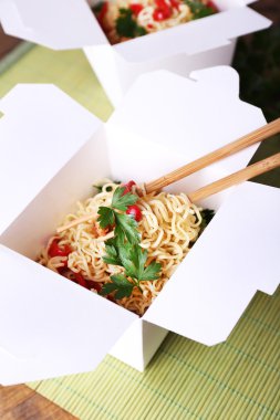 Çin eriştesi ve paket servisi olan restoran kutusunda mat arka plan üzerinde sopa