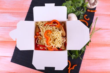Paket servisi olan restoran kutusunda pembe bir arka plan üzerinde siyah mat Çin eriştesi