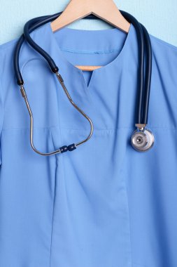 Askı üzerinde mavi arka plan üzerinde stetoskop ile doktor gömlek