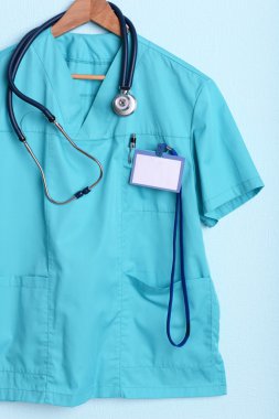 Askı üzerinde mavi arka plan üzerinde stetoskop ile doktor gömlek