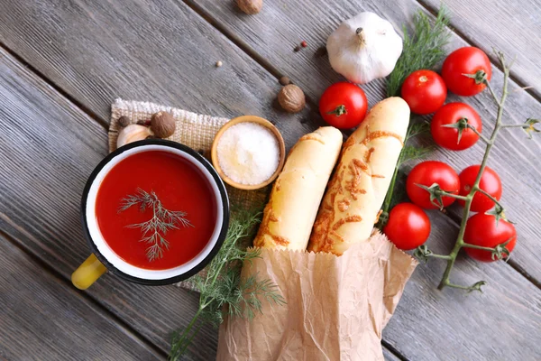 Sumo de tomate caseiro na caneca a cores, pães, especiarias e tomates frescos no fundo de madeira — Fotografia de Stock