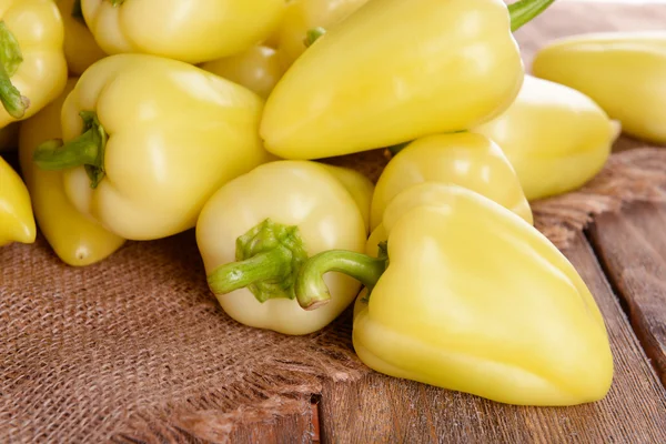Yellow peppers on sackcloth on wooden table — Stock Photo, Image