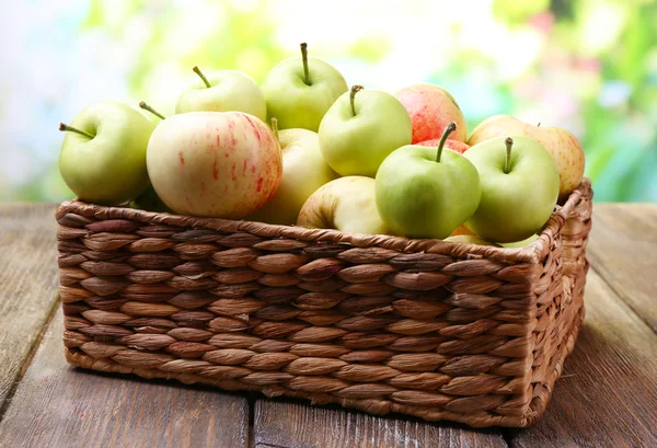 Ripe apples in basket on table on natural background — Stock Photo, Image