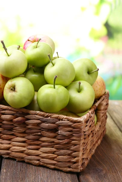 Dojrzałe jabłka kosz na stole na naturalne tło — Zdjęcie stockowe