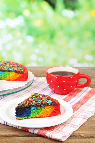 Delicious rainbow cake on plate, on wooden table, on bright background — Stock Photo, Image