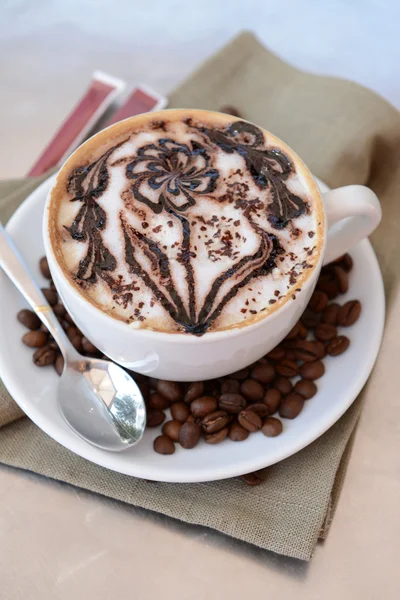 Cup of coffee with cute drawing on table, close up