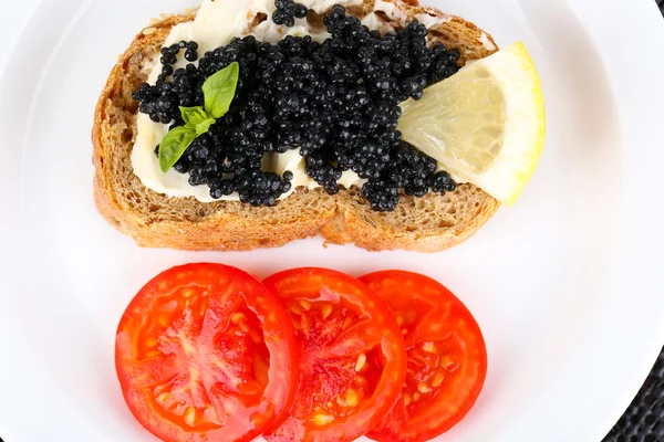 Black caviar and butter on bread with tomatoes on plate closeup — Stock Photo, Image