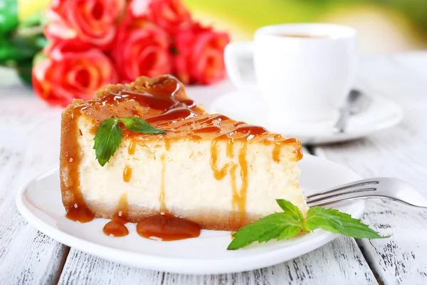 Bolo de queijo em prato e tufo de rosas na mesa no fundo da natureza — Fotografia de Stock