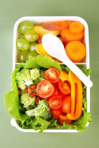 Sabrosa comida vegetariana en caja de plástico sobre mesa de madera verde —  Fotos de Stock