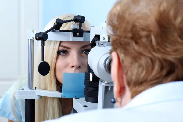 Concepto de optometría: mujer joven y bonita que tiene los ojos examinados por un oftalmólogo —  Fotos de Stock