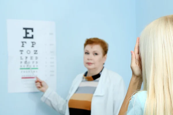 Optometri koncept - ganska ung kvinna med hennes ögon undersökas av ögonläkare — Stockfoto